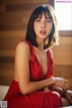 A woman in a red dress sitting on a window sill.