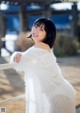 A woman in a white fur coat posing for a picture.