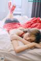 A woman laying on top of a bed in a red dress.