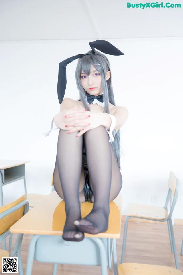 A woman sitting on top of a desk in a classroom.