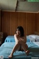 A naked woman sitting on a bed in a bedroom.