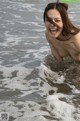 A naked woman in the ocean with her mouth open.