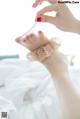 A woman's hand holding a pair of barefoot sandals on a bed.