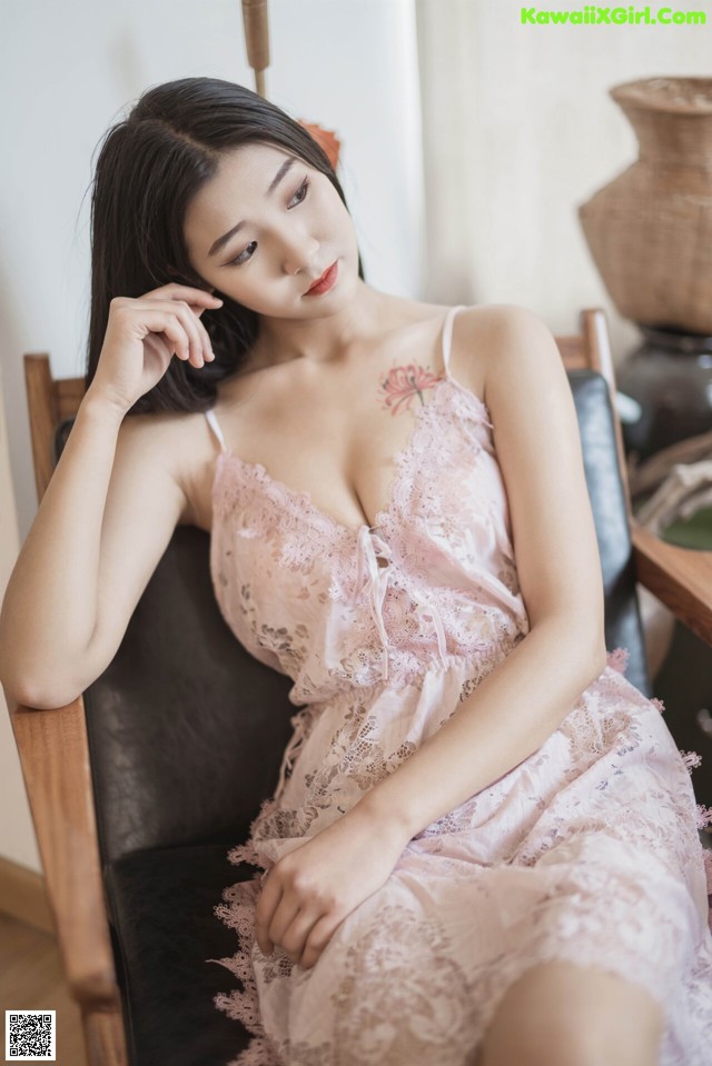 A woman in a pink dress sitting on a chair.